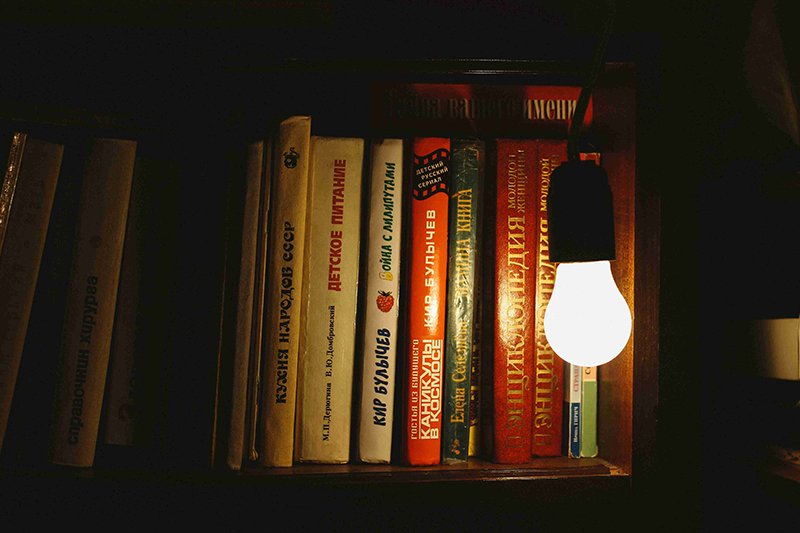 bookshelf illuminated by hanging bulb, cozy reading corner lighting