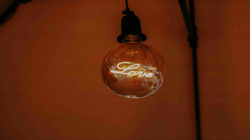 Hanging decorative bulb with "Love" text glowing warmly in a minimalist setting.