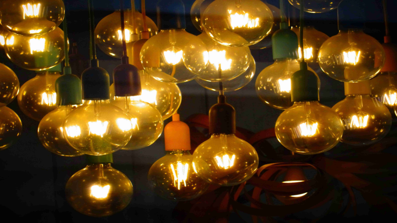 Cluster of glowing LED filament bulbs with various vibrant socket colors.