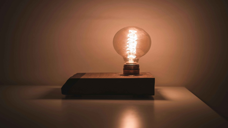 Vintage-style LED bulb on a wooden base, emitting a warm, soft glow.