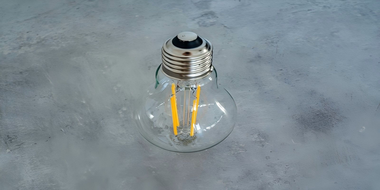 Close-up of LED filament bulb on a gray surface, energy-saving technology.