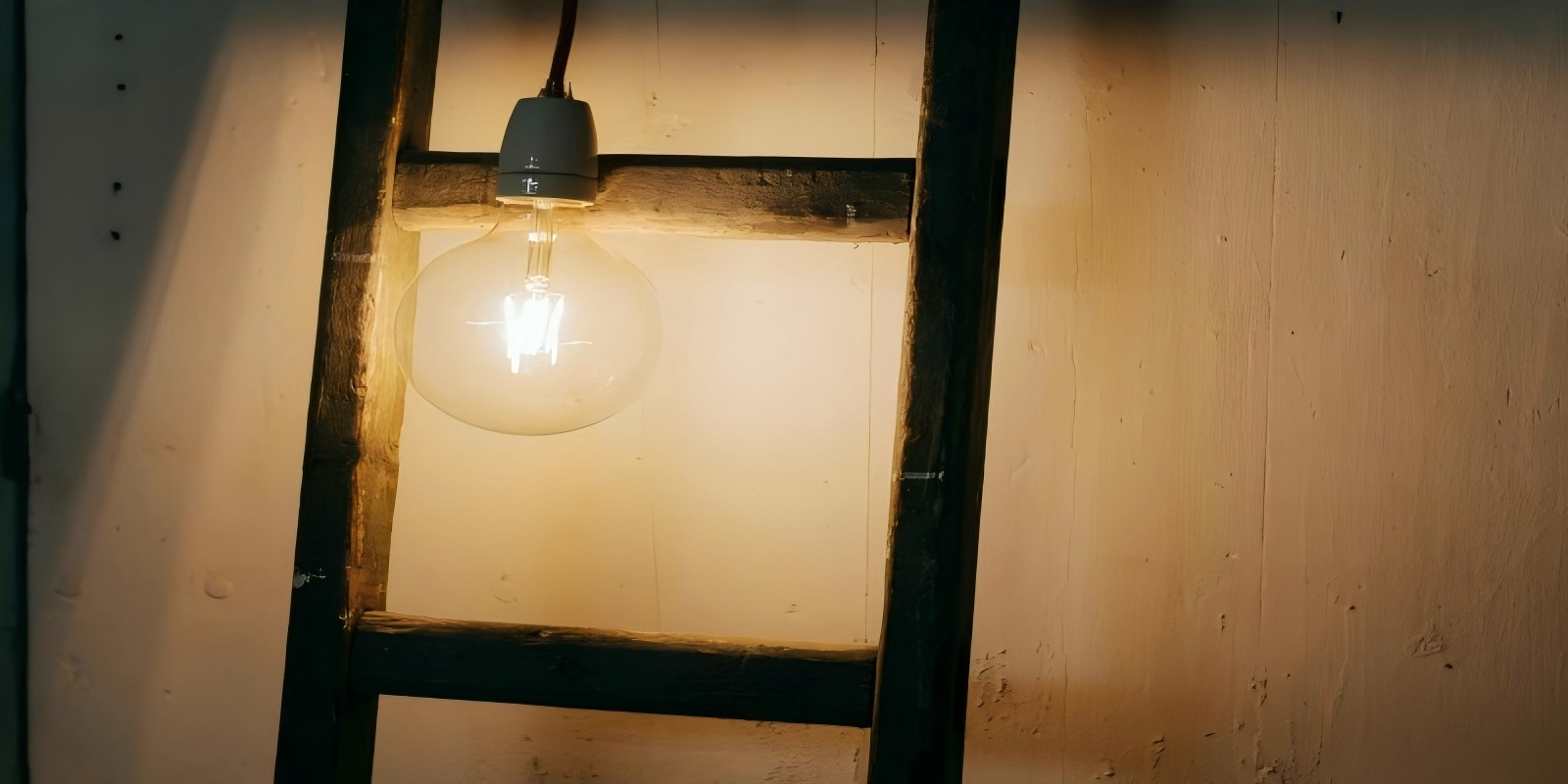 Warm-lit LED filament bulb on a wooden ladder, cozy interior ambiance.