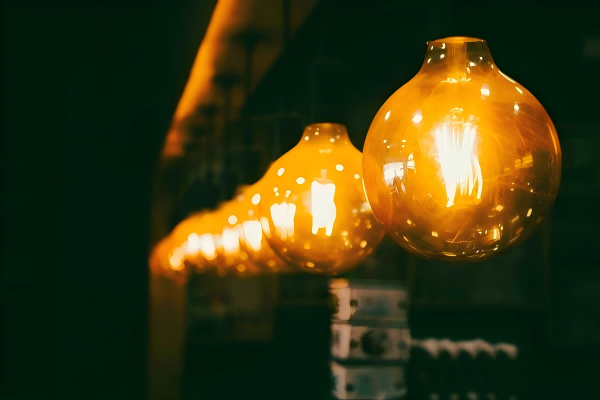 Row of glowing golden LED filament bulbs hanging in a cozy indoor space, creating a warm and inviting atmosphere.