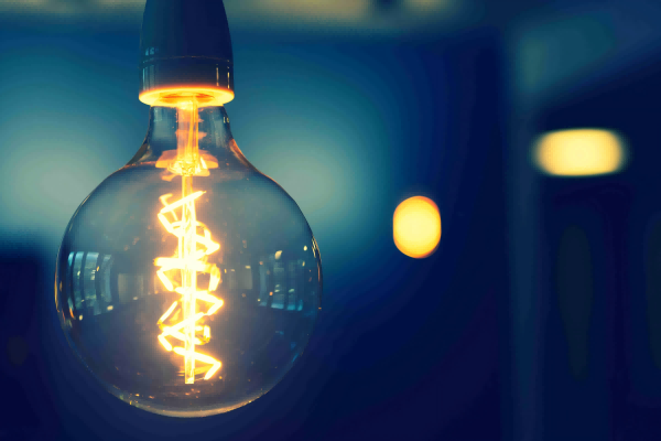 LED filament bulb glowing with a spiral design, surrounded by a deep blue background.