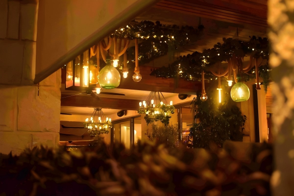 Warmly lit interior with hanging decorative lights and greenery, creating a festive and cozy ambiance.