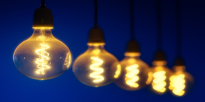 Row of glowing filament bulbs against a deep blue background