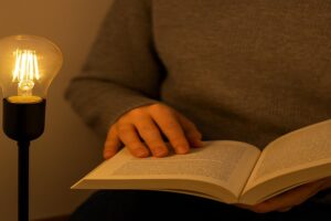 A close-up, comfortable view of a person reading a book under the soft, even light of an Omita LED filament bulb, with no visible glare or shadows on the page